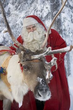 a man dressed as santa claus is standing next to a reindeer