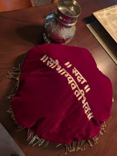 a table topped with a red cloth covered in writing next to a silver vase and book