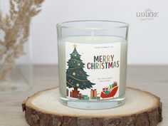 a candle with a merry christmas card on it sitting on top of a wooden slice