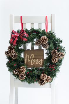 a white chair with a christmas wreath on it and a wooden sign that says mrs