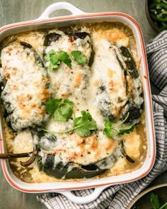 a casserole dish filled with chicken, cheese and green vegetables on a table