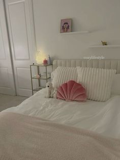 a white bed topped with pillows and a stuffed animal