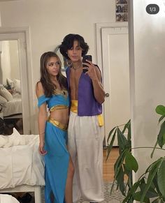 two people in costumes taking a selfie with a cell phone while standing next to each other