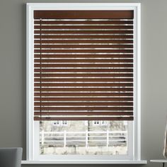 a living room with grey walls and wooden blinds on the window sill in front of it