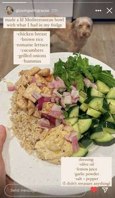 a white plate topped with meat and veggies next to a person's hand