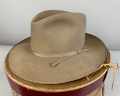 Always a classic, this 1940's "Stetson" Open Road fedora will top off any suit or western outfit! The beaver felt fedora is a pleasant warm sandy beige color - like lost in a dust storm. This hat also features a narrow ribbed tone-on-tone grosgrain silk ribbon band and matching taped edge.  It has a leather inner hat band and is unlined. By Stetson and with the original owner's name handwritten in the leather sweatband - what a fun piece of history! Includes the original box! This hat is in grea Vintage Fitted Felt Hat For Ranch, Vintage Fitted Fedora For Ranch, Fitted Vintage Fedora For Ranch, Fitted Western Style Six-panel Hat Bands, Classic Cream Fitted Top Hat, Vintage Fitted Hat For Ranch, Fitted Vintage Hat For Ranch, Vintage Style Fitted Beige Fedora, Vintage Fitted Beige Fedora