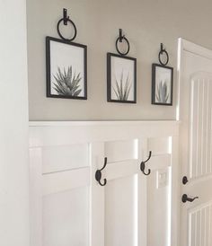 three framed pictures hang on the wall above a white door with black handles and hooks