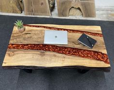 a wooden table topped with a laptop computer next to a potted plant on top of it