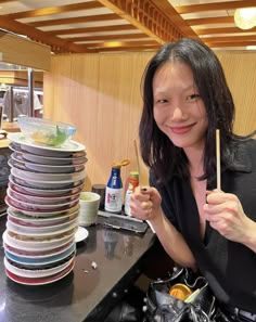 a woman is holding chopsticks in front of stacks of plates