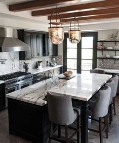 a large kitchen with marble counter tops and black cabinets