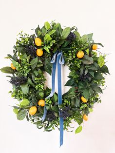 a wreath with oranges and greenery on it hanging from the side of a wall