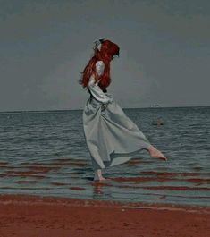 a woman with red hair is standing in the water