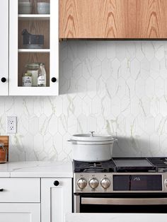 a stove top oven sitting inside of a kitchen next to white cabinets and cupboards