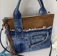 a handbag made out of old jeans with fringes on the handles and sides