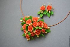 an orange flower necklace and earring set on a gray surface with gold beading