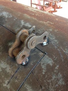 an old rusted piece of metal on the ground next to a wooden table with chairs in the background