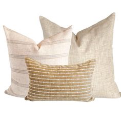 three pillows in different colors and patterns on a white background, each with a gold stripe