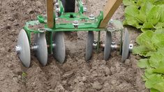 a plow being used to plant lettuce in the ground with two wheels