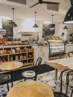 the inside of a bakery with tables and chairs in front of it, people working behind the counter