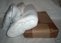 an unmade bed with white towels on it and a brown box in the middle