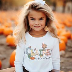 Long Sleeve Toddler Thanksgiving Shirt for boys or girls. A delightful and personalized garment that will bring extra joy to your child's Christmas. This charming Thanksgiving t-shirt displays your child "is thankful," capturing the essence of the thanksgiving season. But what makes it truly special is the adorable turkey, pumpkins and falling leaves that surround your child's name. Each t-shirt is personally and uniquely designed. It's a whimsical scene that will ignite the imagination and fill Personalized Cotton T-shirt For Fall, Cute Name Print Tops For Fall, Cute Tops With Name Print For Fall, Casual Personalized T-shirt For Fall, Personalized Casual T-shirt For Fall, Customizable Cute Tops For Fall, Long Sleeve Name Print Tops For Fall, Long Sleeve Tops With Name Print For Fall, Toddler Thanksgiving Shirt