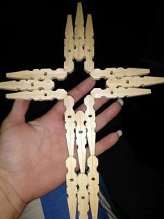 a hand holding a wooden model of a cross