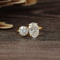 two diamond earrings sitting on top of a wooden table