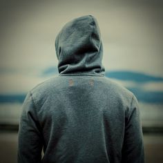 a person wearing a hoodie looking out at the ocean