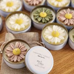 many small tins with flowers in them sitting on a wooden table next to each other