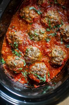 meatballs in marinara sauce with parsley on top, sitting in the slow cooker