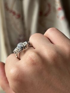 “Art Deco” was an era marked by extravagance and innovation. The Art Deco style itself was an eclectic mix of heavy geometric shapes, with curved ornamental elements. The resulting silhouettes were often monolithic but elegant, with applied decorative elements. This Moonstone and Sapphire Edwardian Conversion Ring is a wonderful example of this iconic Art Deco style. Crafted in 20 carat white gold, this ring immediately captures the gaze with its dazzling array of miniature pearls and sapphire stones haloing a truly luminescent cabochon moonstone. What makes this treasure particularly special is that it is a conversion piece; the beautiful moonstone center was once part of an antique brooch. Now, with the use of a 14 carat gold replica shank, it has been transformed into the glorious ring Formal Open Ring With Unique Design, Fine Jewelry Ring With Unique Design, Elegant Open Ring Made Of Metal, Luxury Formal Ring With Unique Design, Luxury Formal Rings With Unique Design, Elegant Open Band Metal Jewelry, Luxury Rings With Unique Design For Formal Occasions, Elegant Metal Jewelry With Ring Detail, Elegant Metal Rings With Intricate Design