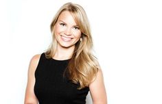 a woman in a black dress smiling for the camera with her hands on her hips