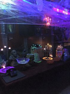 a table with candles and decorations on it in a dark room filled with halloween decorations