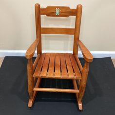 a wooden rocking chair sitting on top of a black floor next to a white wall