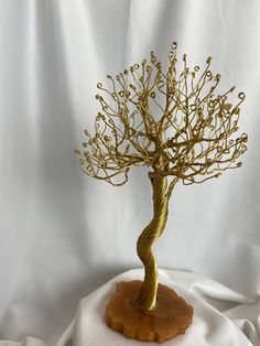 a gold wire tree sculpture sitting on top of a white cloth