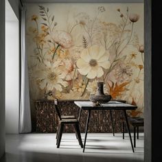 a dining room table with two chairs and a vase on it in front of a floral wall mural