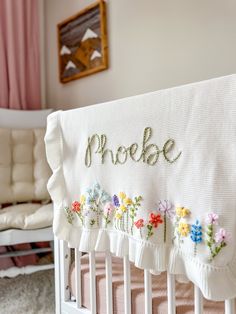 a white crib with flowers on it and the word probee written in cursive writing