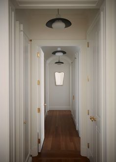 an empty hallway with white walls and wood floors