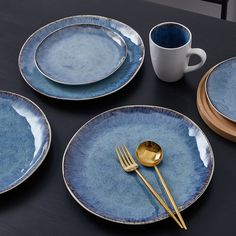 blue plates and goldware are arranged on a black table