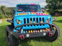 a blue jeep with rubber ducks on it's front grill and bumper guards is parked in the grass