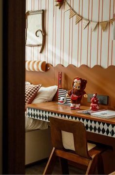 a teddy bear sitting on top of a wooden desk next to a chair and lamp