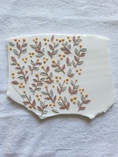 a white plate with yellow flowers and leaves painted on the side, sitting on a towel