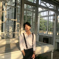 a young man standing in front of a building with lots of glass panes on it