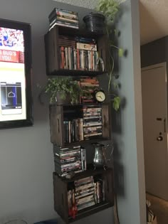 a book shelf filled with lots of books next to a wall mounted clock and potted plant