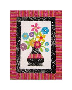 a vase filled with colorful flowers sitting on top of a pink and black table cloth