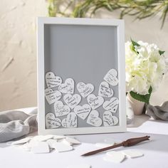 a white frame sitting on top of a table filled with paper hearts and other items