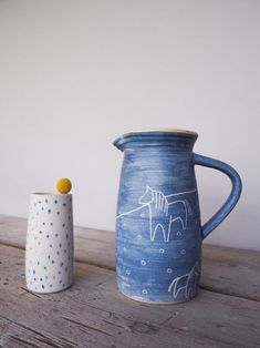 two vases sitting on top of a wooden table next to each other, one with a horse painted on it