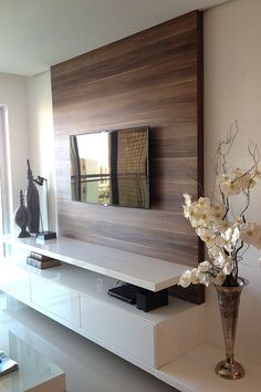 a vase with flowers in it sitting next to a wall mounted mirror on a shelf