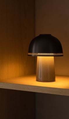 a black lamp sitting on top of a wooden shelf