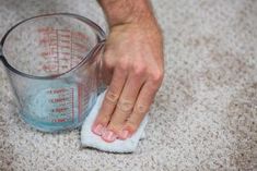 a person is cleaning the floor with a cloth and a measuring cup on top of it